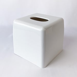 May include: A white square tissue box holder with a rectangular opening on the top.