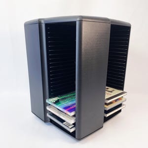 May include: Black CD storage tower with two rotating sections. The tower holds multiple CDs and has a capacity of 100 discs. The tower is made of durable plastic and has a sleek, modern design.
