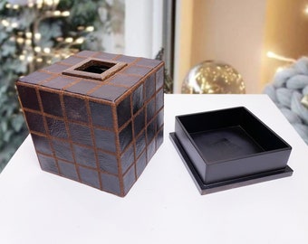 May include: A brown leather tissue box cover with a checkered pattern and a black interior. The cover is open and the interior is visible.