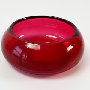 May include: A deep red glass bowl with a rounded shape and a smooth, glossy finish.