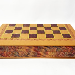 May include: A rectangular chess set with a brown and yellow chequered board. The board is framed with a decorative border. The sides of the set feature a colourful, patterned design. The set is displayed on a white background.