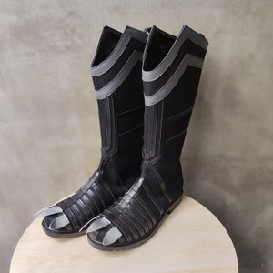 May include: A pair of black knee-high boots with a geometric pattern. The boots have a pointed toe and a low heel.