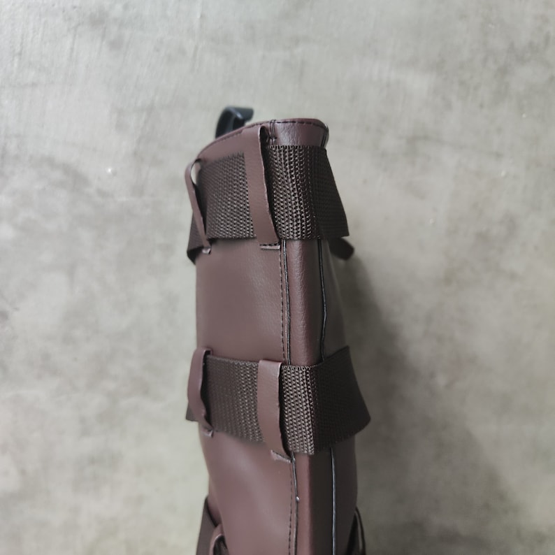 May include: A brown leather bag with adjustable straps and a buckle closure. The bag has a textured surface and a simple design.