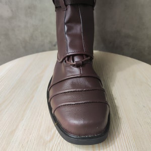 May include: Close-up of the brown leather toe of a riding boot with a black sole.