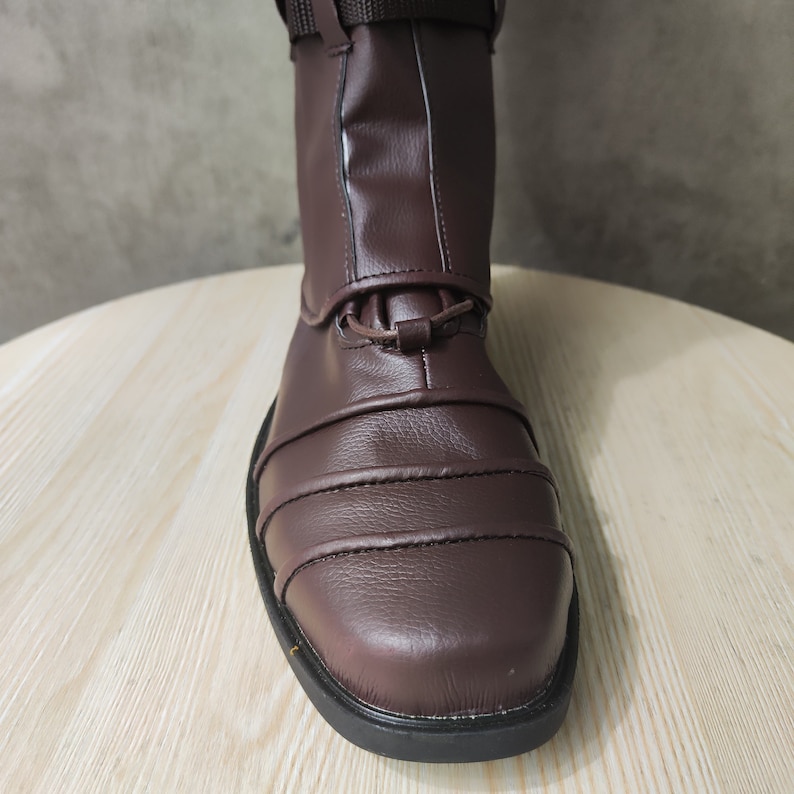 May include: Close-up of the brown leather toe of a riding boot with a black sole.
