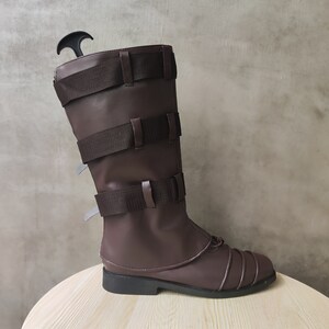 May include: Brown leather boots with multiple straps and buckles. The boots have a pointed toe and a thick sole.