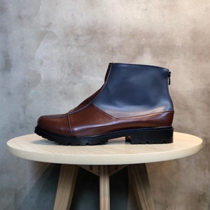 May include: A brown and blue leather ankle boot with a zipper on the back. The boot has a thick black sole.