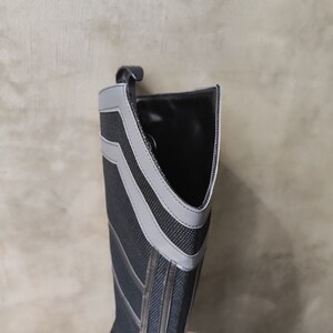 May include: Black and gray tall boot with a gray stripe design. The boot is made of a textured fabric and has a pointed toe.