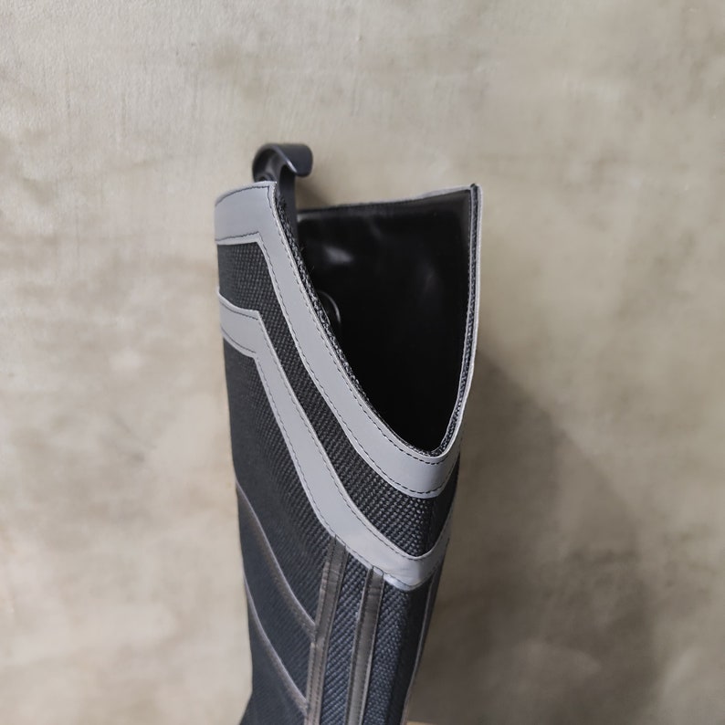 May include: Black and gray tall boot with a gray stripe design. The boot is made of a textured fabric and has a pointed toe.