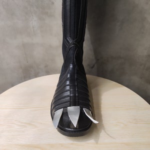 May include: Black leather boots with silver claws on the toes. The boots have a textured design and are knee-high.
