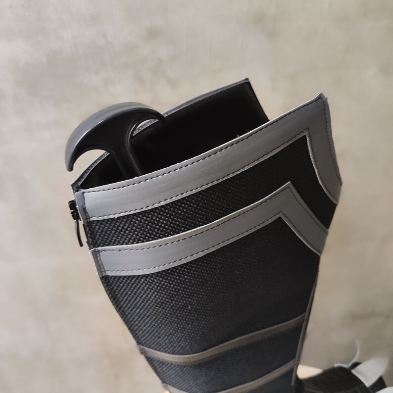 May include: Black boot with a zipper and gray reflective stripes. The boot is made of a textured fabric and has a black shoe horn inside.