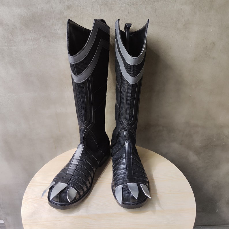 May include: A pair of black boots with grey accents and pointed toes. The boots have a textured fabric and a zipper on the back.
