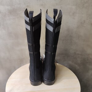 May include: A pair of black knee-high boots with gray accents and zipper closures.