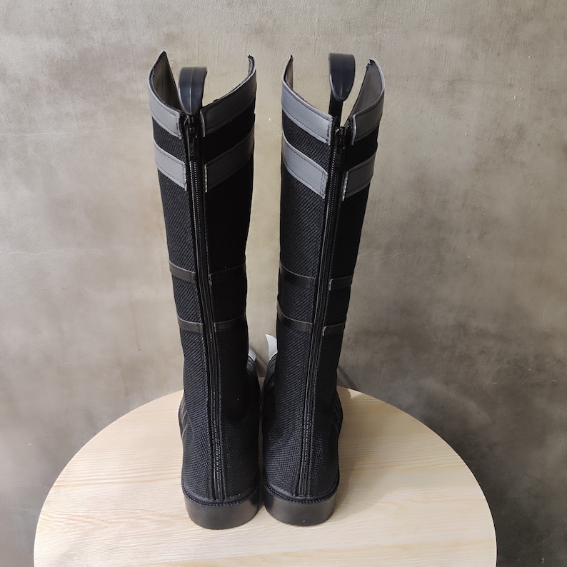 May include: A pair of black knee-high boots with gray accents and zipper closures.