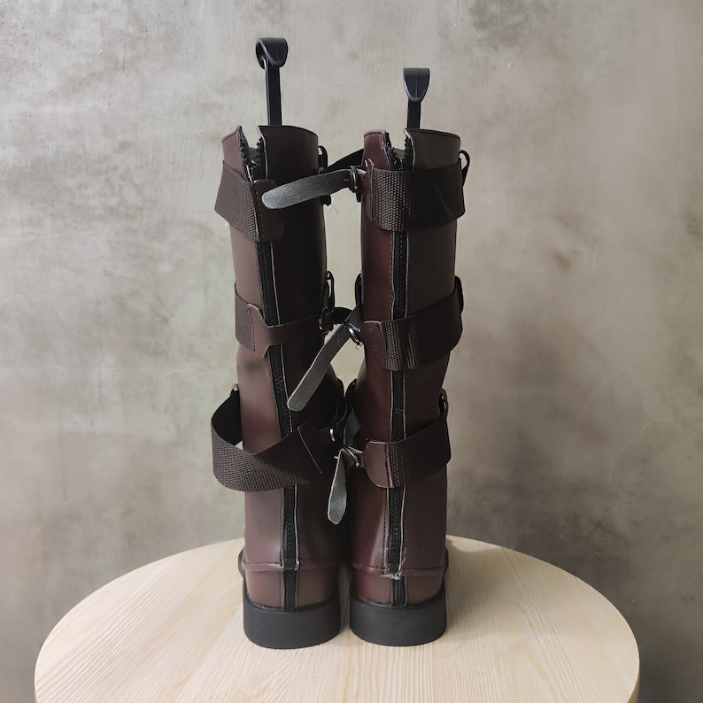 May include: A pair of brown leather boots with multiple buckles and straps. The boots have a zipper on the back and a pointed toe.