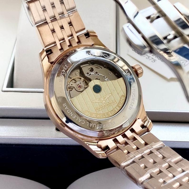 May include: Rose gold wristwatch with a transparent back, revealing the internal mechanism. The watch has a metal strap and a round face. The text "PERPETUAL CALENDAR" and "SWISS MADE" are visible.