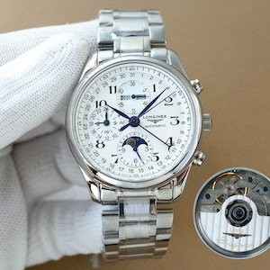 Op de afbeelding: Een zilverkleurig Longines automatisch horloge met een witte wijzerplaat, meerdere subwijzerplaten en een datumweergave. Het horloge heeft een roestvrijstalen band en een aparte weergave van het binnenwerk.