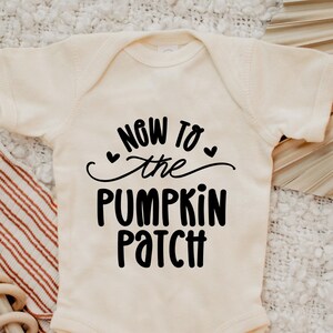 Puede incluir: Un body blanco para bebé con texto negro que dice "Now to the Pumpkin Patch" con dos pequeños corazones a cada lado de la palabra "the".