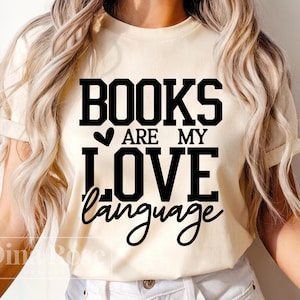 May include: A white t-shirt with black text that reads "Books are my love language" with a small heart symbol before the word "are".