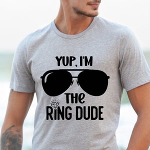 May include: A gray t-shirt with the text "Yup, I'm the Ring Dude" and a pair of sunglasses printed on it.