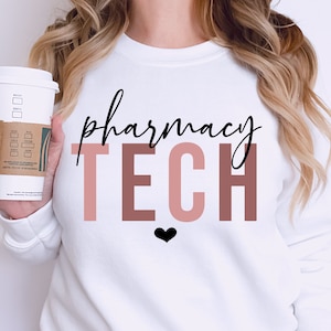 May include: White sweatshirt with the text "pharmacy TECH" in black and pink lettering. A small black heart is below the text.