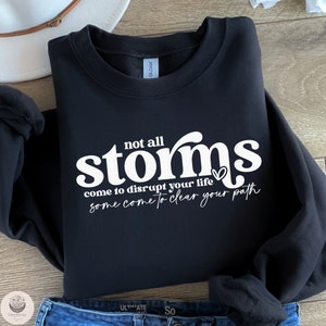 May include: Black sweatshirt with white text that reads "not all storms come to disrupt your life some come to clear your path".