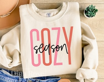 May include: A cream coloured sweatshirt with the text "cozy season" in pink, red and black lettering.