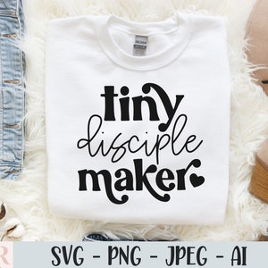 Könnte beinhalten: Weißes T-Shirt mit schwarzem Text, der "tiny disciple maker" mit einem kleinen Herzen lautet.
