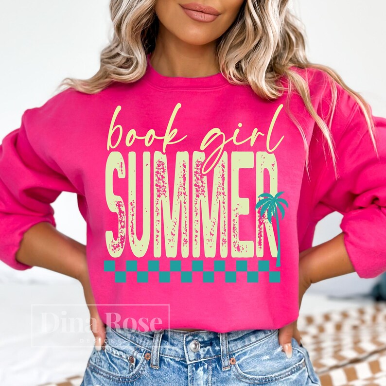 May include: A bright pink sweatshirt with the words "book girl SUMMER" in a light green font. A teal palm tree graphic is on the right side of the word "SUMMER". A teal and white checkered pattern is at the bottom of the word "SUMMER".