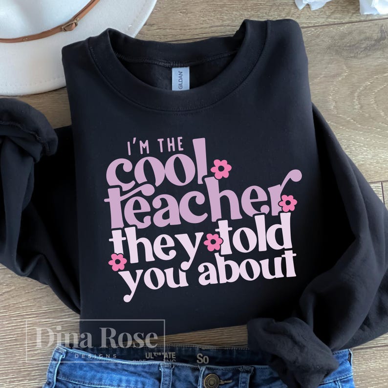 May include: Black sweatshirt with the text "I'm the cool teacher they told you about" in pink letters with pink flower accents.
