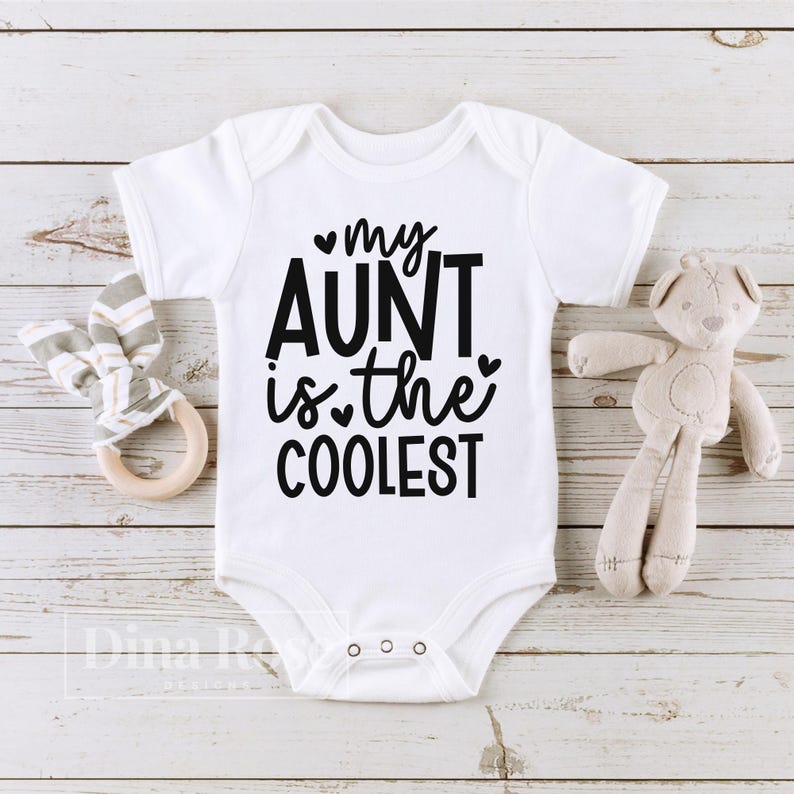 May include: White baby onesie with black text that reads "my aunt is the coolest" with a small heart symbol before "my" and "the".