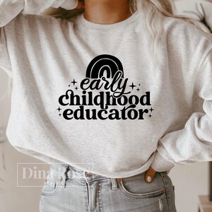 May include: A gray sweatshirt with a rainbow graphic and the text "early childhood educator" in black.