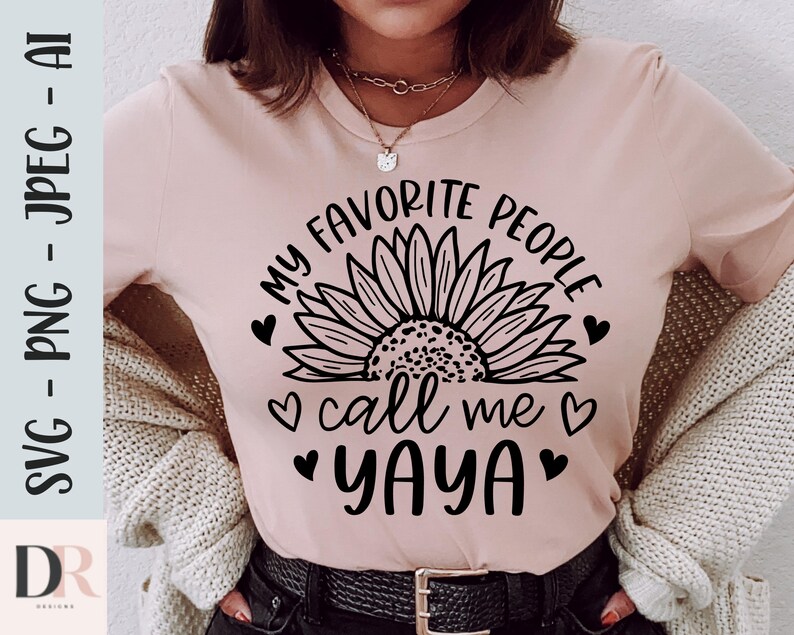 K&ouml;nnte beinhalten: Ein pinkfarbenes T-Shirt mit einer schwarzen Sonnenblumengrafik und dem Text "Meine Lieblingsmenschen nennen mich Yaya" mit Herzen um den Text.