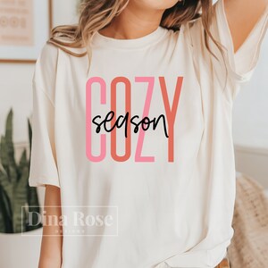 May include: A white t-shirt with the text "COZY season" in pink and red lettering.