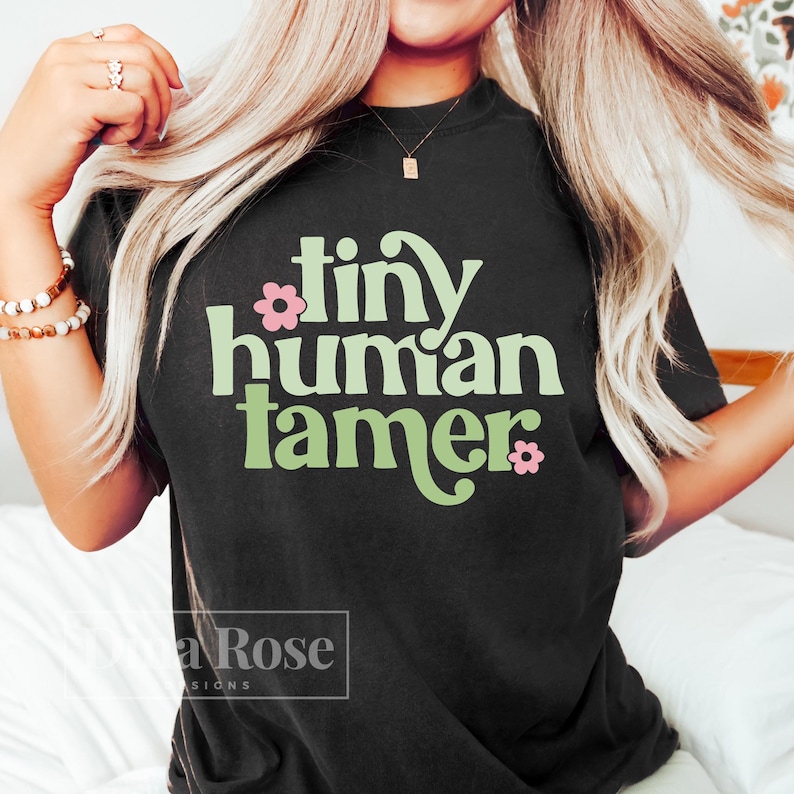 May include: A black t-shirt with a green and pink graphic that says "tiny human tamer".