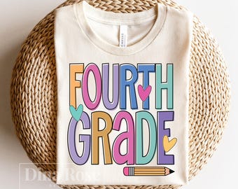 May include: Cream-colored t-shirt with the words "FOURTH GRADE" in colorful block letters. The design includes hearts and a pencil illustration. The shirt is folded on a woven, circular surface.