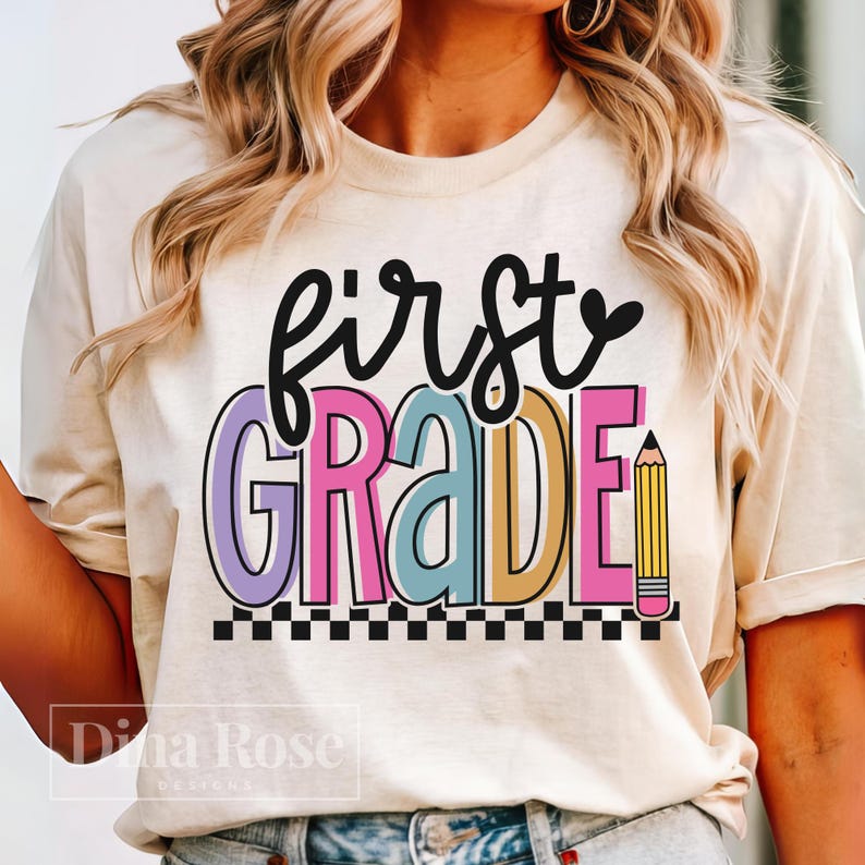 K&ouml;nnte beinhalten: Cremefarbenes T-Shirt mit den Worten "first GRADE" in einem farbenfrohen, verspielten Design. Das Wort "first" ist in schwarzer Schrift, und "GRADE" ist in Lila, Rosa, Blau und Gelb. Eine Bleistiftgrafik befindet sich rechts.
