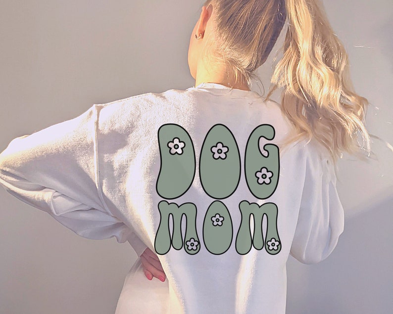 May include: White sweatshirt with a green "DOG MOM" graphic with white flowers on the back.