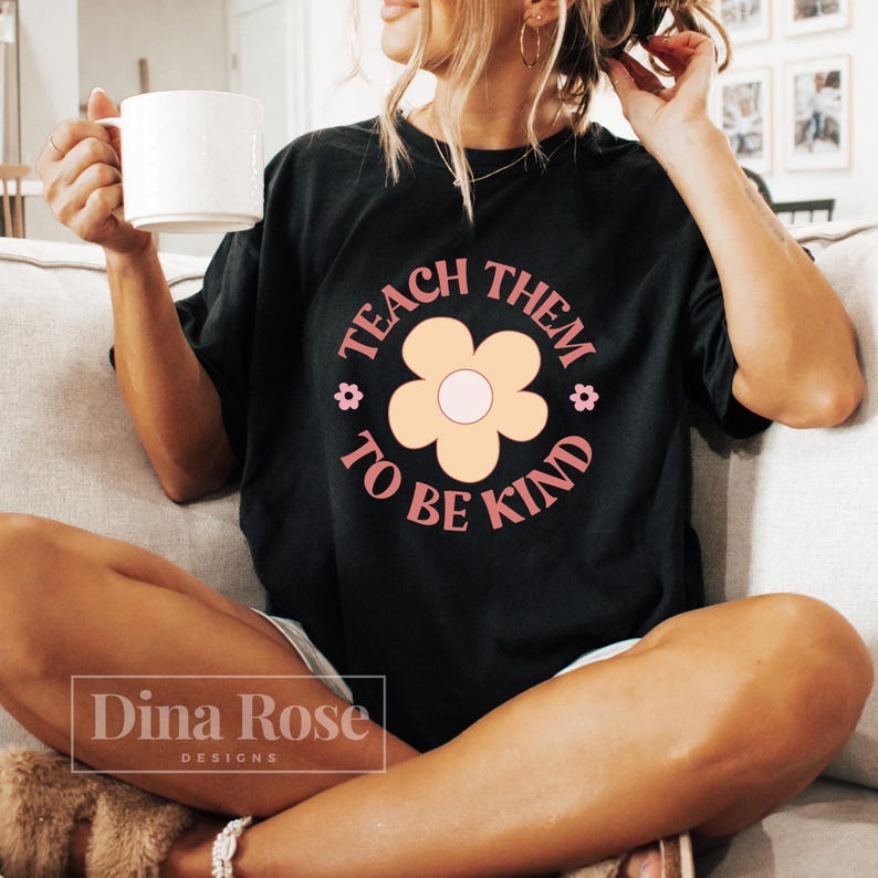 May include: A black t-shirt with a pink and yellow flower graphic and the text "Teach Them To Be Kind".