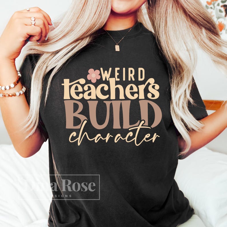 May include: Black t-shirt with the text "Weird teachers build character" in pink and brown lettering with a small pink flower graphic.