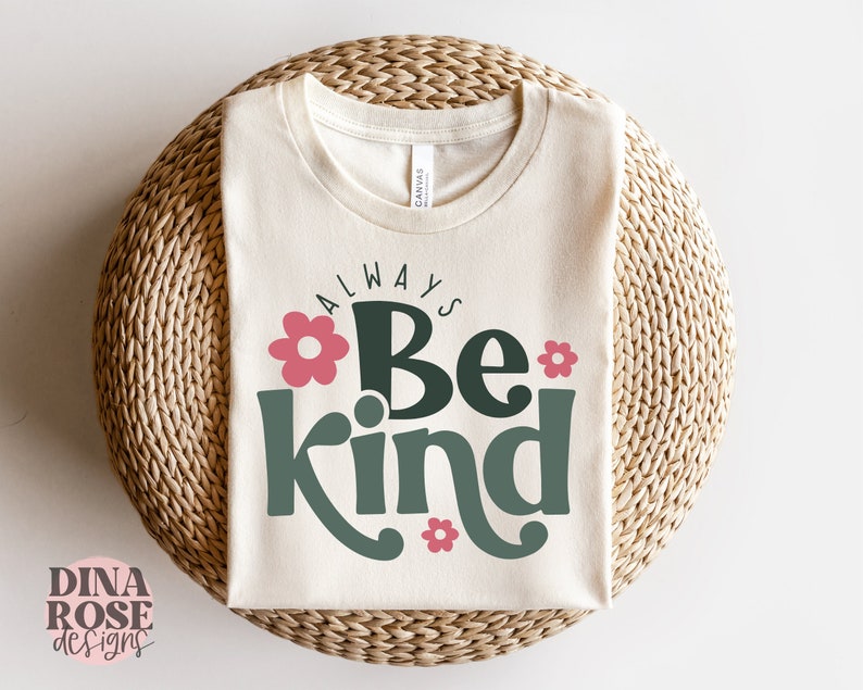 May include: A white t-shirt with the text "Always Be Kind" in green and pink lettering with flower accents.