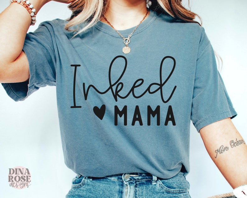 May include: A blue t-shirt with the text "Inked Mama" in black lettering with a small heart in between the words.