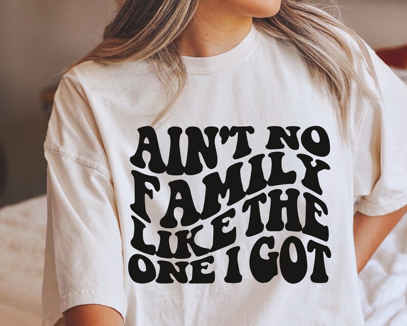 Pu&ograve; includere: Maglietta bianca con testo nero che recita "Ain't no family like the one I got" in un font retr&ograve;.