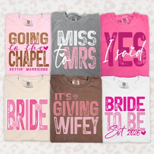 May include: Six t-shirts in various colors, each with a different bridal-themed graphic. The shirts feature phrases like "Going to the Chapel," "Miss to Mrs," and "Bride to Be." The text is in shades of pink, brown, and white.