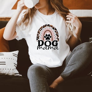 May include: White t-shirt with a rainbow design featuring a paw print and the text "DOG mama".