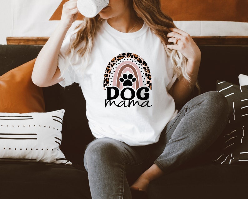 May include: White t-shirt with a rainbow design featuring a paw print and the text "DOG mama".