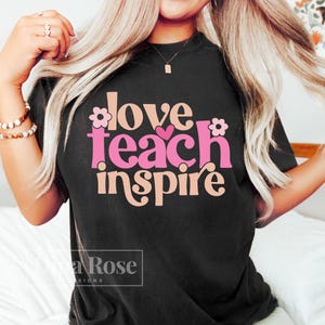 May include: Black t-shirt with the text "love teach inspire" in pink and peach with flower accents.