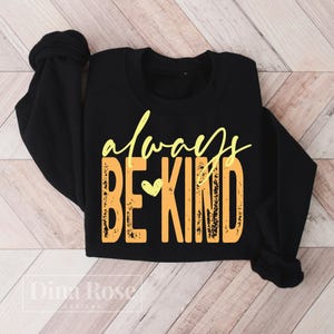 May include: Black sweatshirt with the words "always BE KIND" in yellow and orange lettering. The word "always" is in a cursive font, and the words "BE KIND" are in a block font. A small yellow heart is between the words "BE" and "KIND".