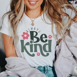 May include: White t-shirt with the text "Always Be Kind" in green letters with pink flowers.