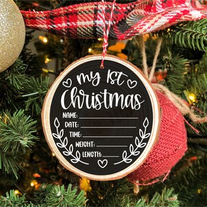 Pu&ograve; includere: Un ornamento natalizio in legno bianco e nero con il testo "My 1st Christmas" e righe vuote per nome, data, ora, peso e lunghezza.